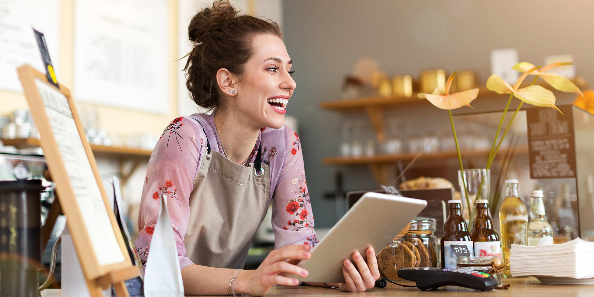 woman smiling in a shop holding a tablet device | Digital business skills