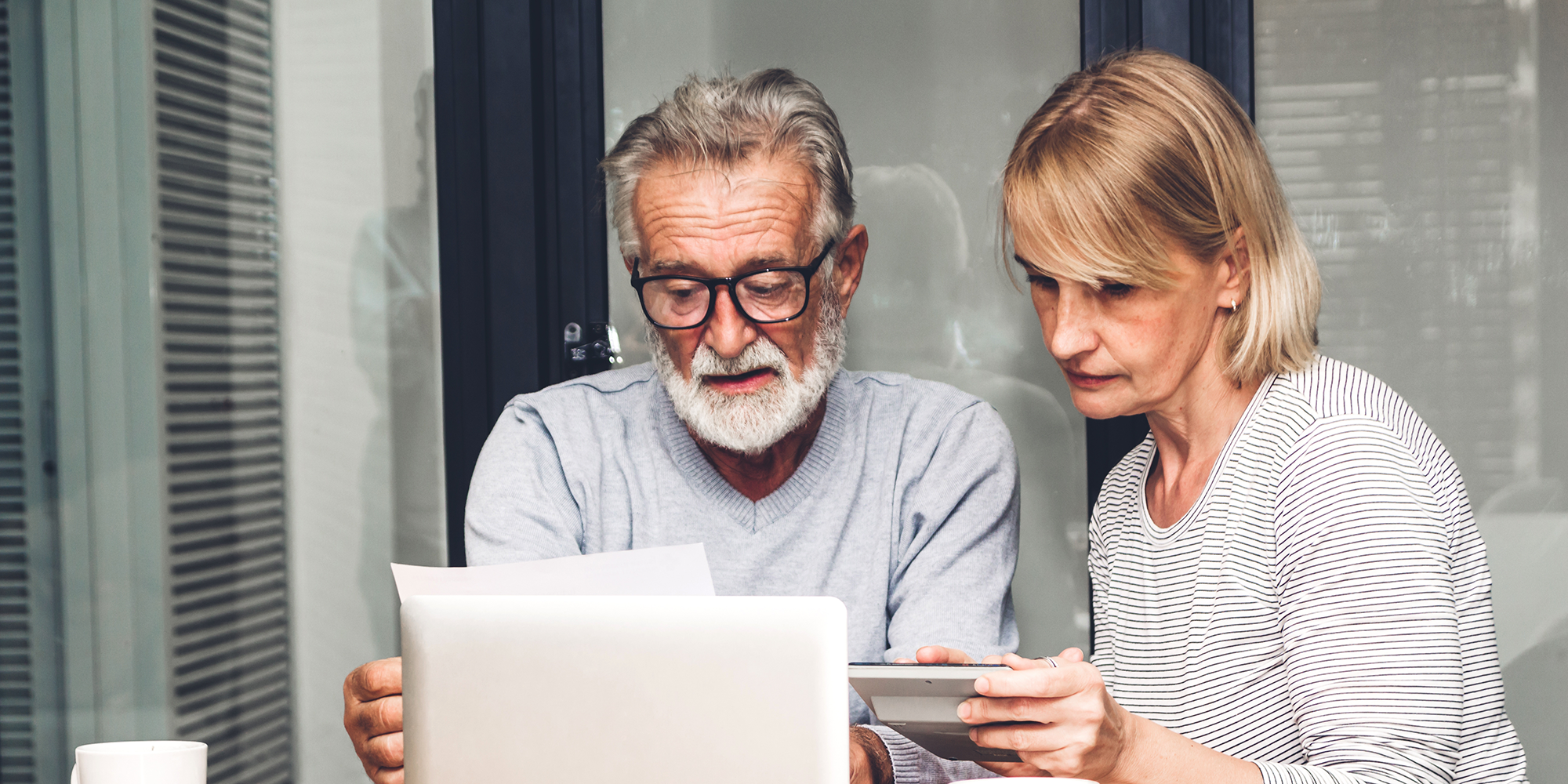 older man and woman sitting at a table doing their banking online
