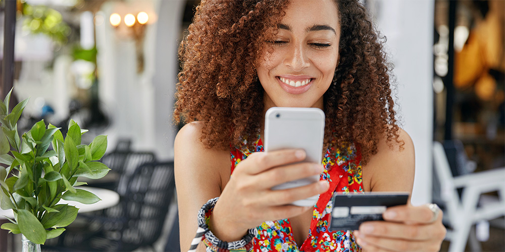 Lady smiling as she makes a purchase on her phone