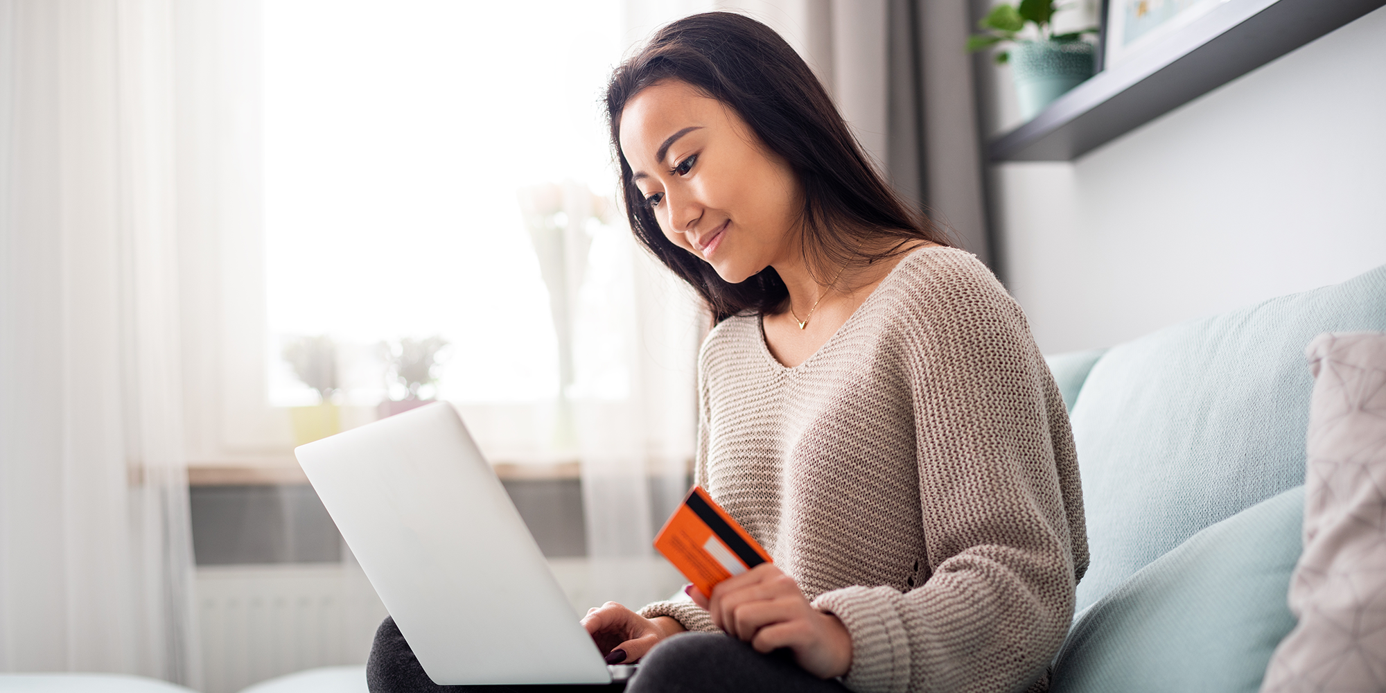 woman looking at a laptop holding a debit card