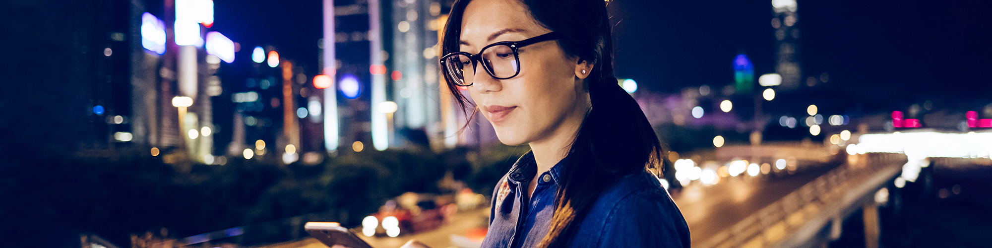 Lady looking at her smartphone in front of a cityscape | Using digital devices course | Digital Wings