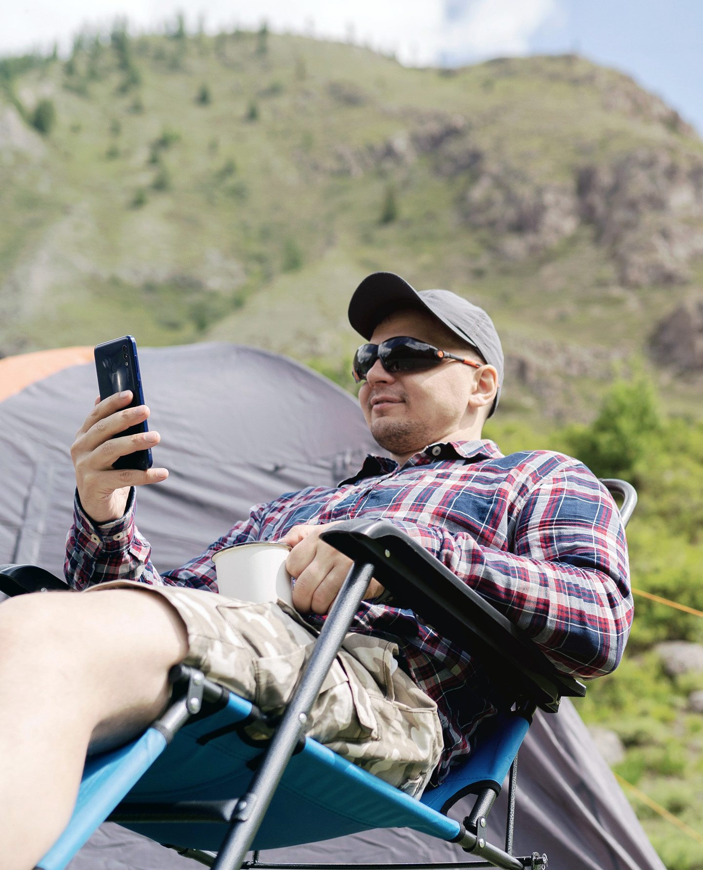 Camper, checking his phone while in nature