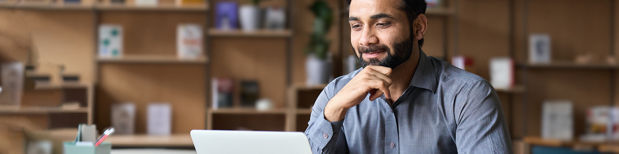 Gentleman looking at his laptop with hand on chin in thought