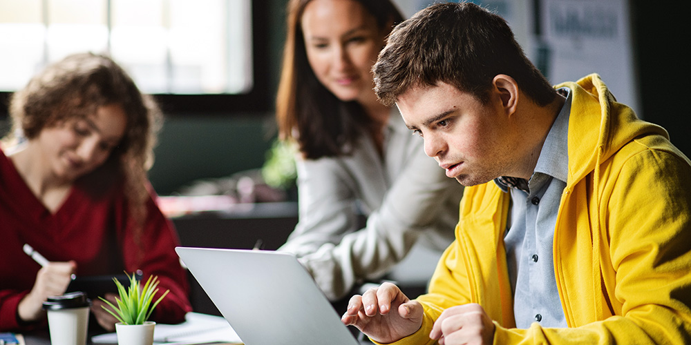 Learner receiving help to use a laptop