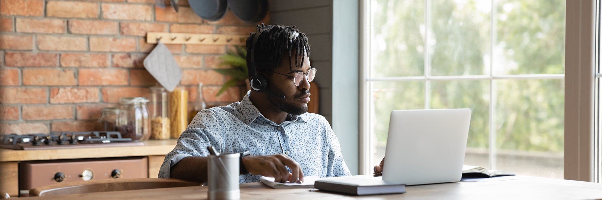 Man sitting at a table looking at his laptop | digital wings social media for small businesses