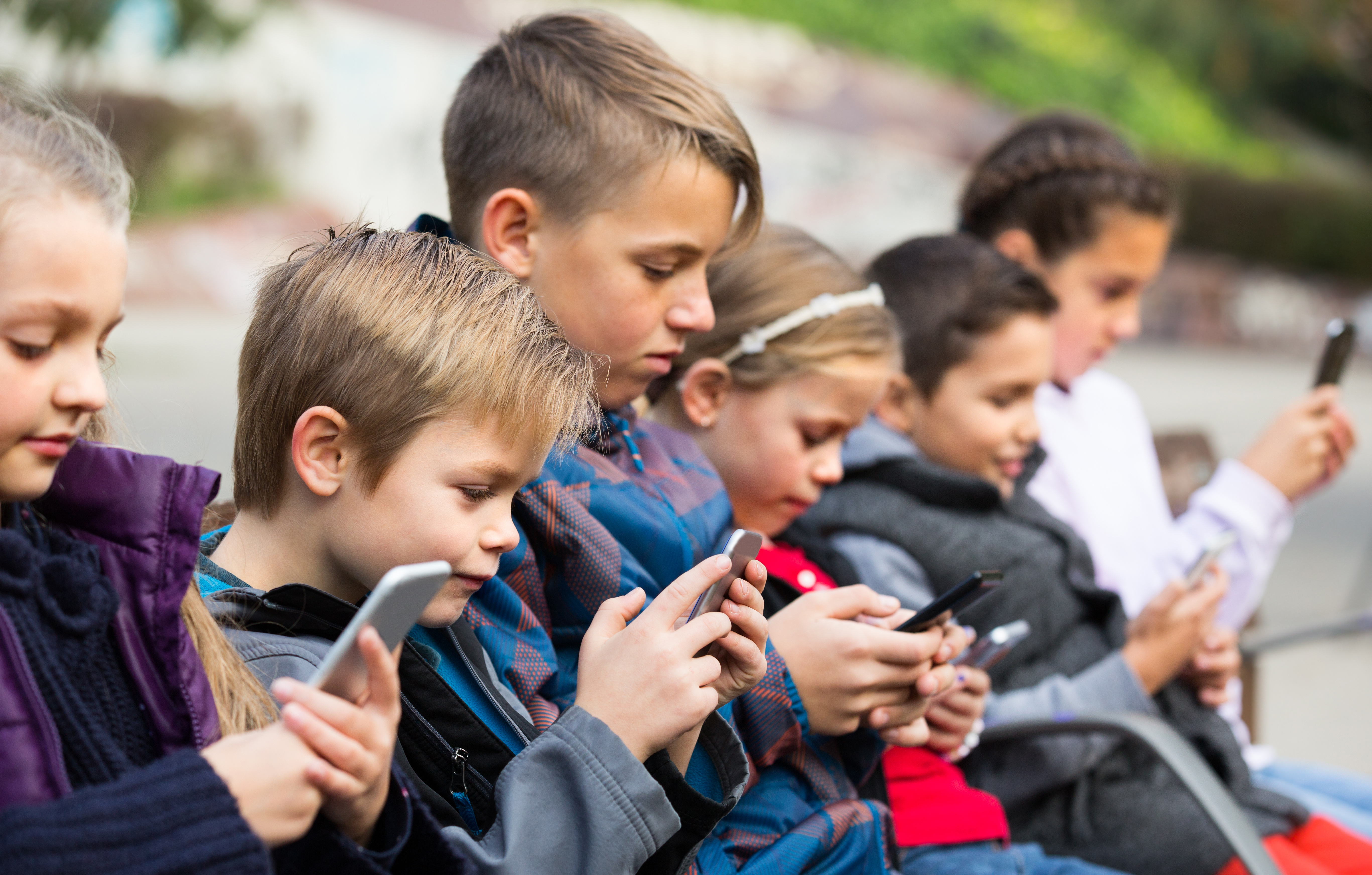 Children in a row looking at their smartphones | Digital Wings keeping children safe online