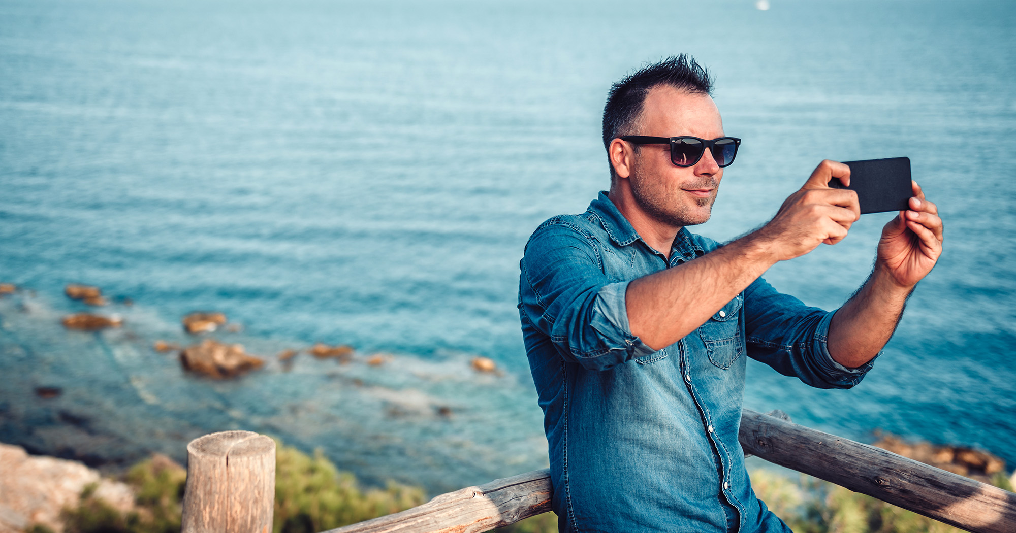 Man taking a selfie in front of a seaside scene | Social media training course | Digital Wings