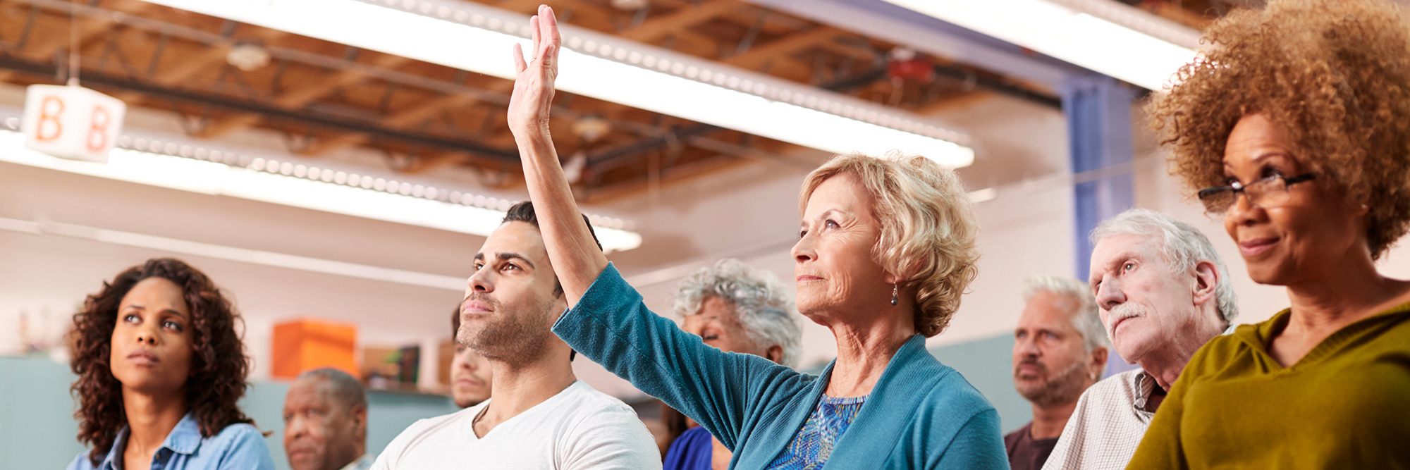 woman sitting in a row of people holding her hand up