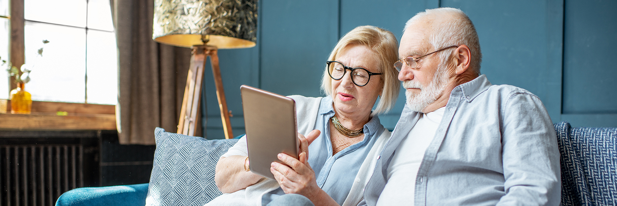older man and woman looking at a tablet sitting on the sofa  | Digital Wings blog | What is streaming