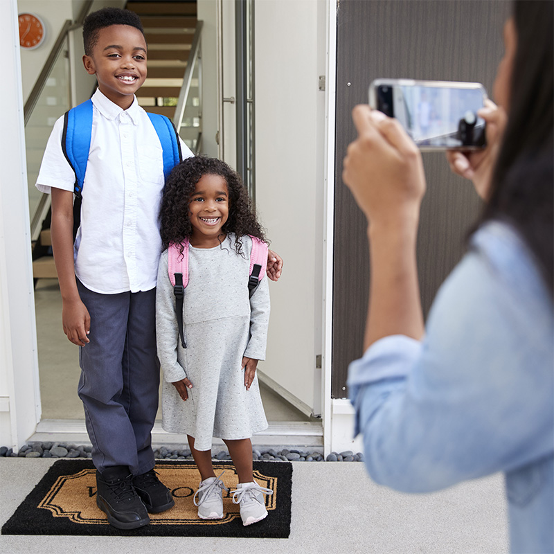 Two kids having their photo taken as they leave for school