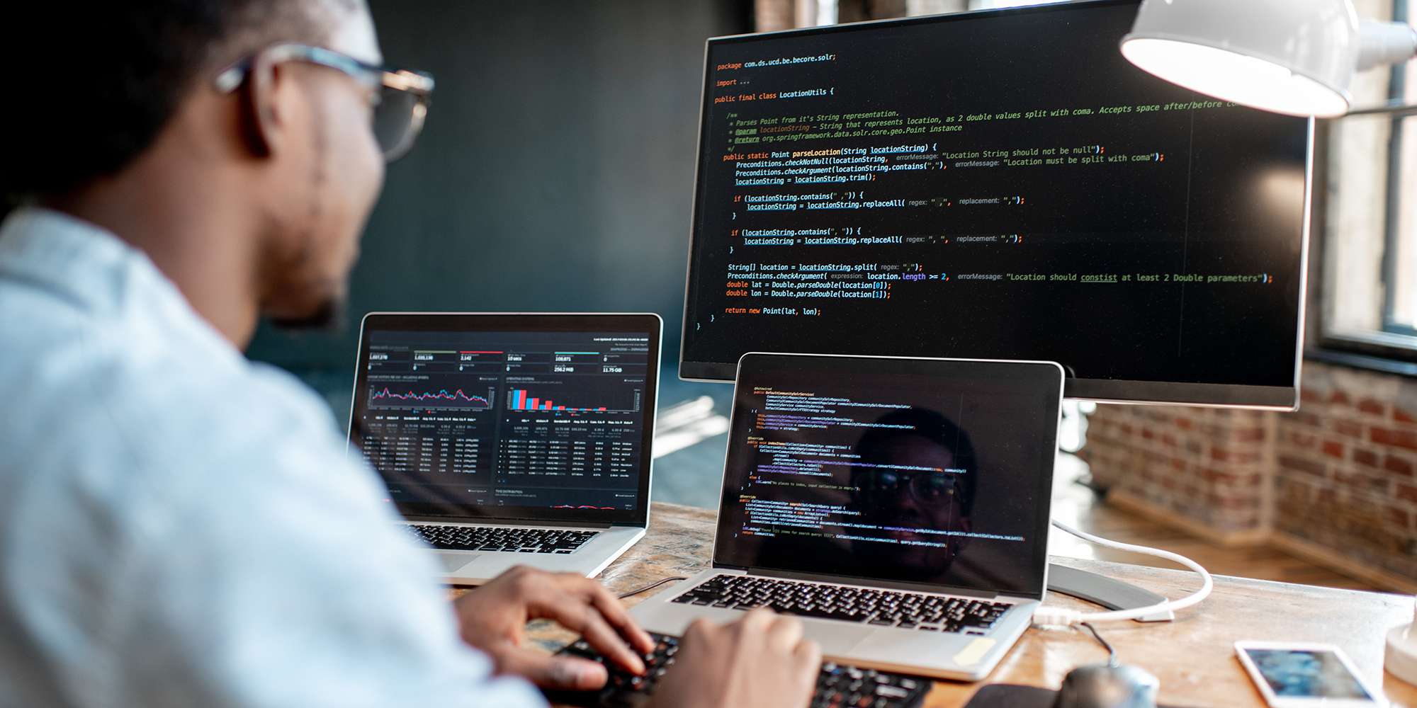 man looking at a three screens with code on them | digital business skills