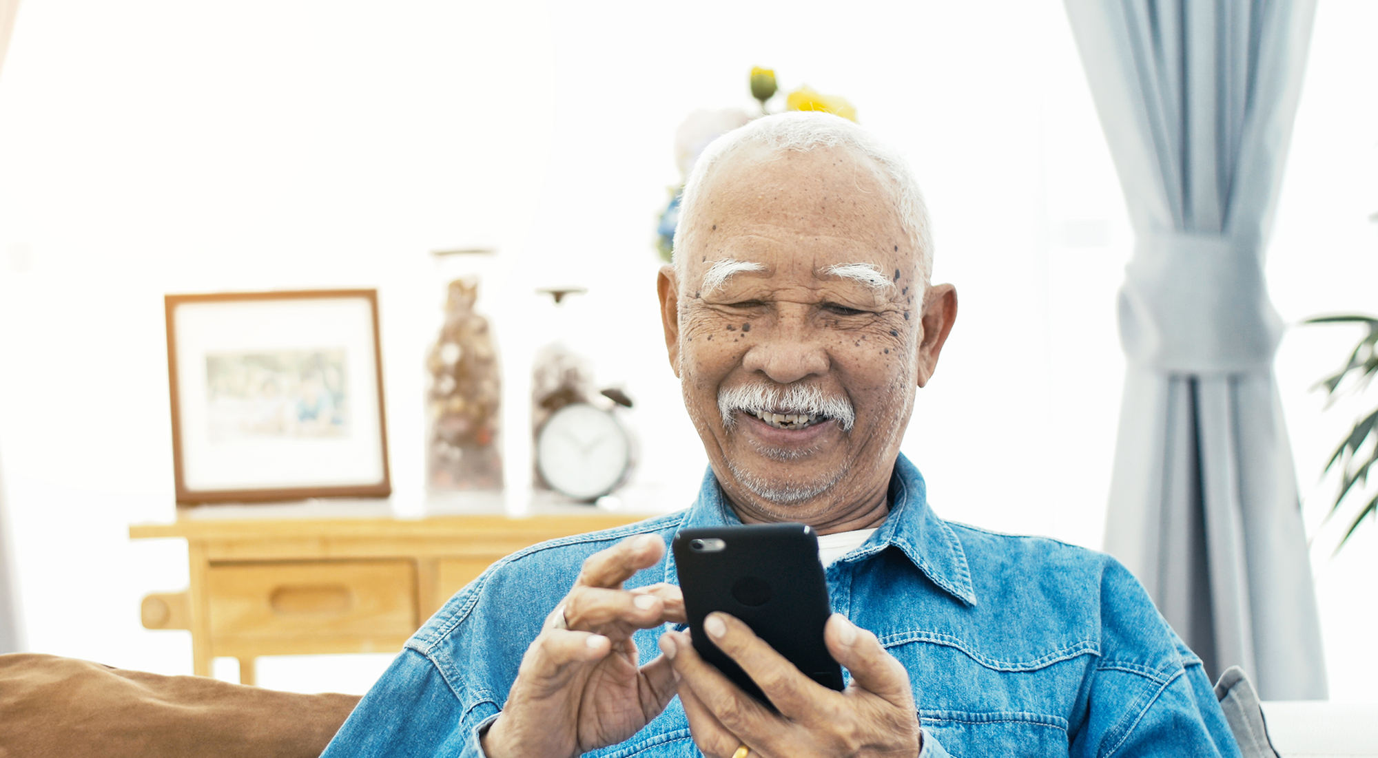 older man smiling looking at his smartphone | smartphone for a grandparent