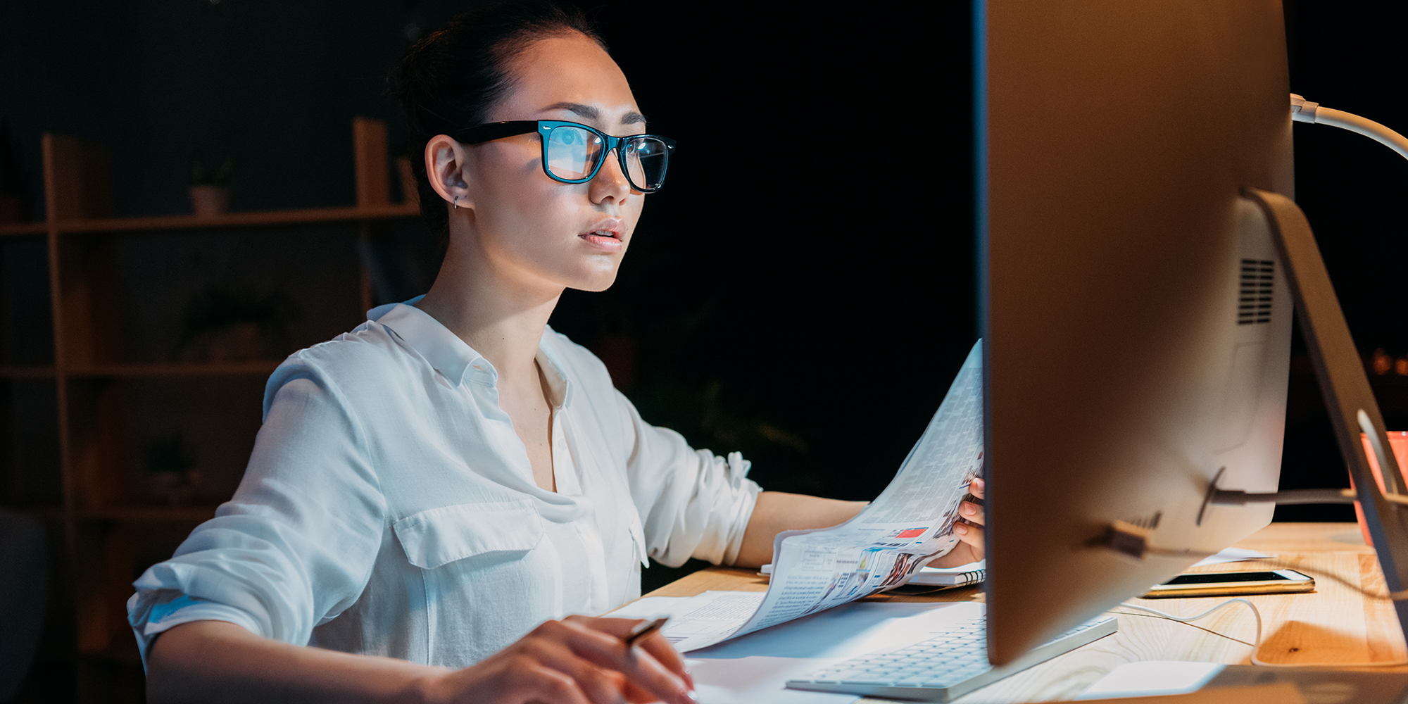 woman sitting in a dark room concentrating t something on her computer screen