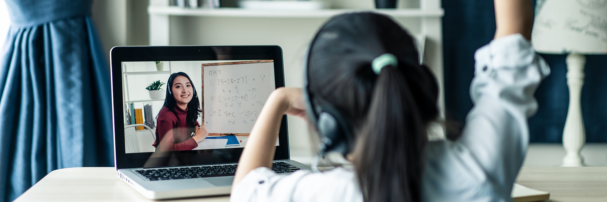 girl with her arm raised watching a virtual lesson on her laptop | Digital classroom