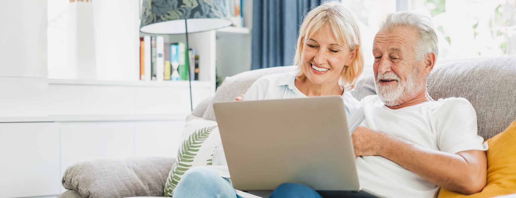 older couple sitting on a sofa smiling looking at a laptop  | Ultimate guide to Essential digital skills | Digital Wings blog