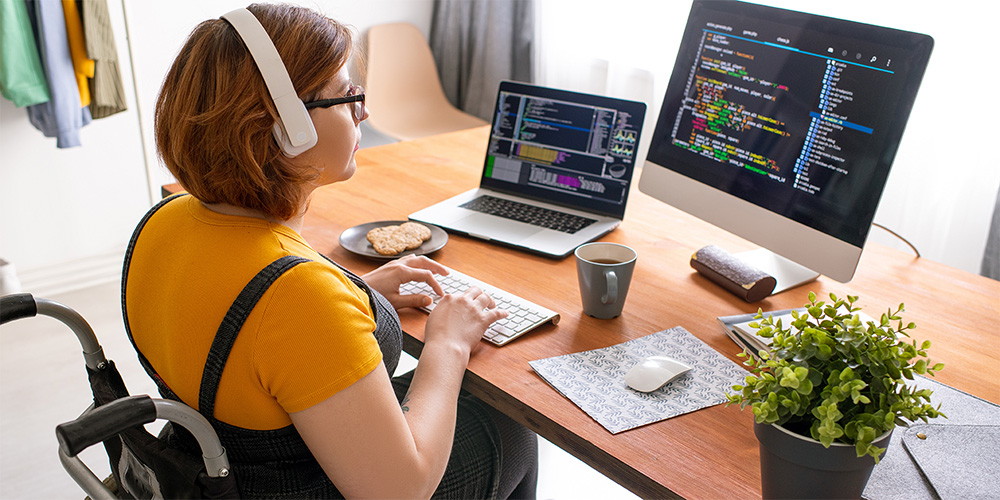 Lady looking at two screens of code