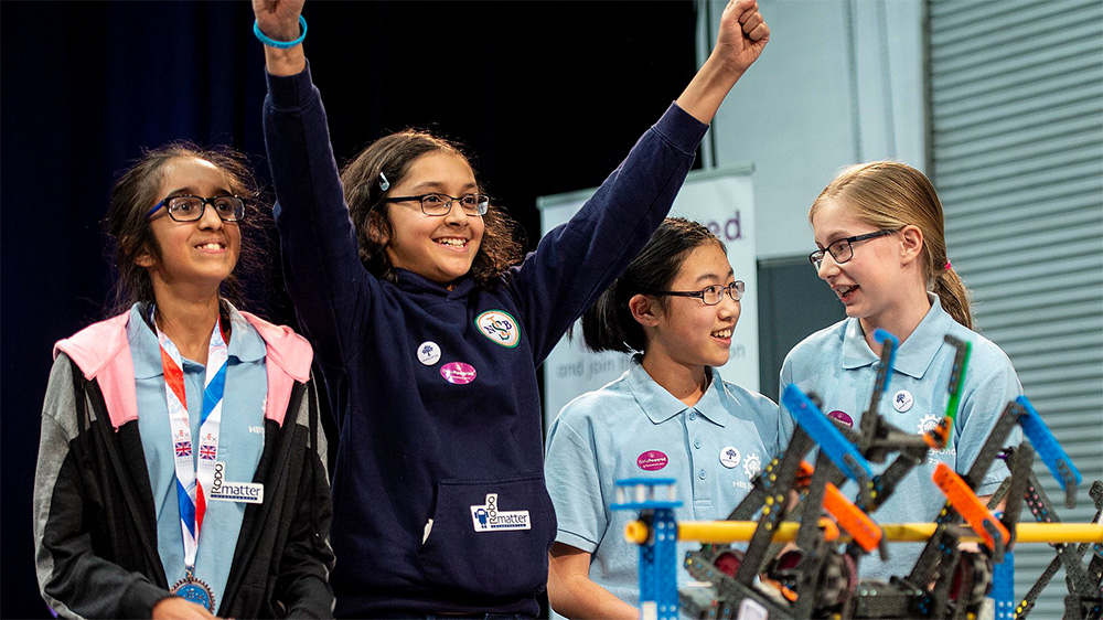 Girl celebrating with her team after winning a robotics competition