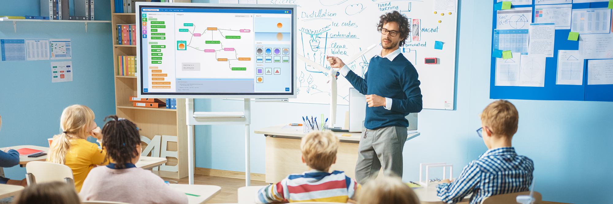 teacher pointing at an interactive whiteboard in front of his class