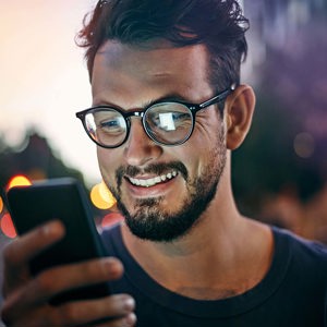 man with glasses looking at his smartphone