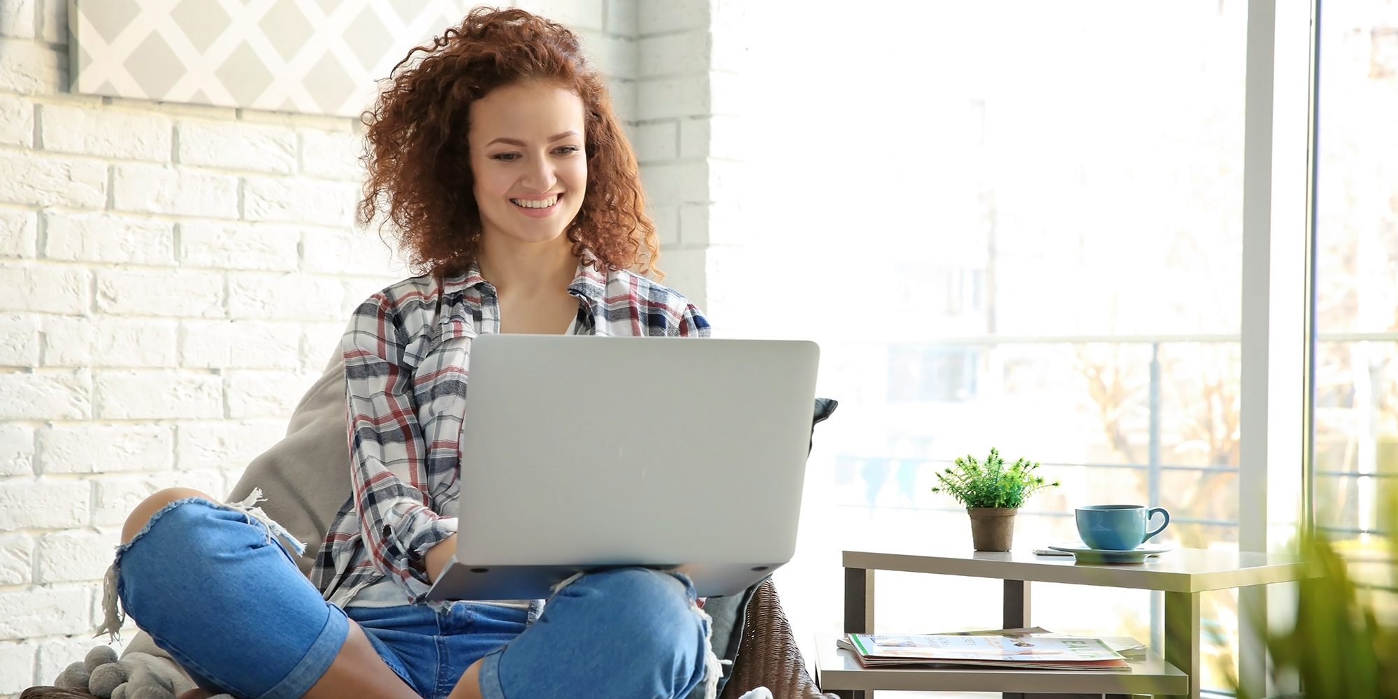 woamn sitting cross legged looking at a laptop