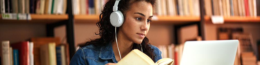 student studying with headphone on in a library