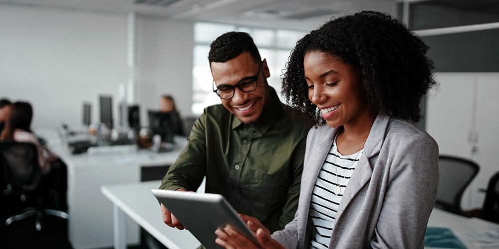 Colleagues smiling at something received on a tablet