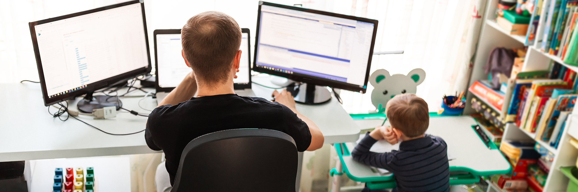 Man and young boy sitting at their desks next to each other in a home office | How to stay focused WFH