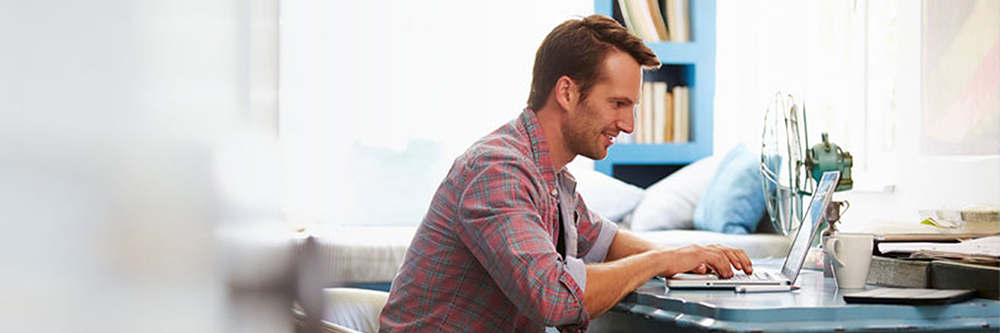 man typing on a laptop sitting at a table