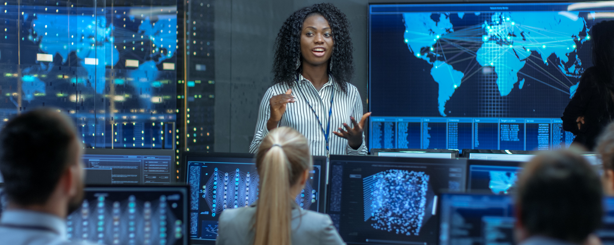 woman taling to her team standing in front of a large screen | Digital business skills