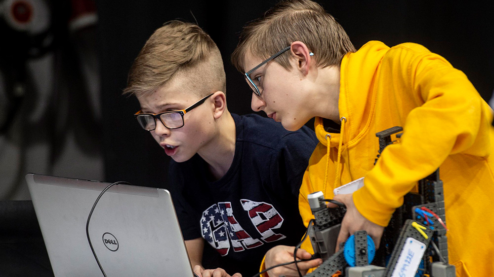 Two boys working on a robot